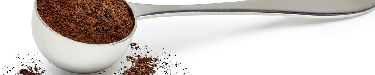 Silver coffee scoop overflowing with ground coffee